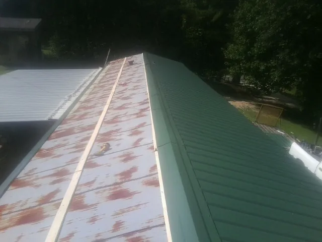 Old rusted panels beside newly installed green metal roofing — Wind Damage Roof Repair by Roofing Brothers in Ashippun