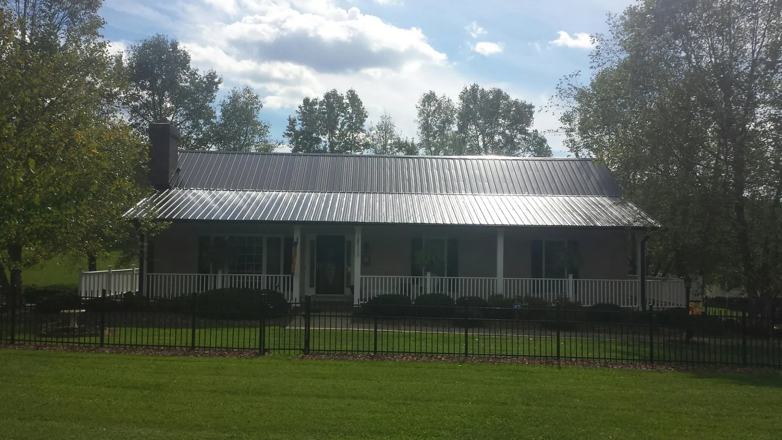 Gray metal roof on a brick ranch with a full width front porch — Gutter Guard Installation work by our crew in Ashippun