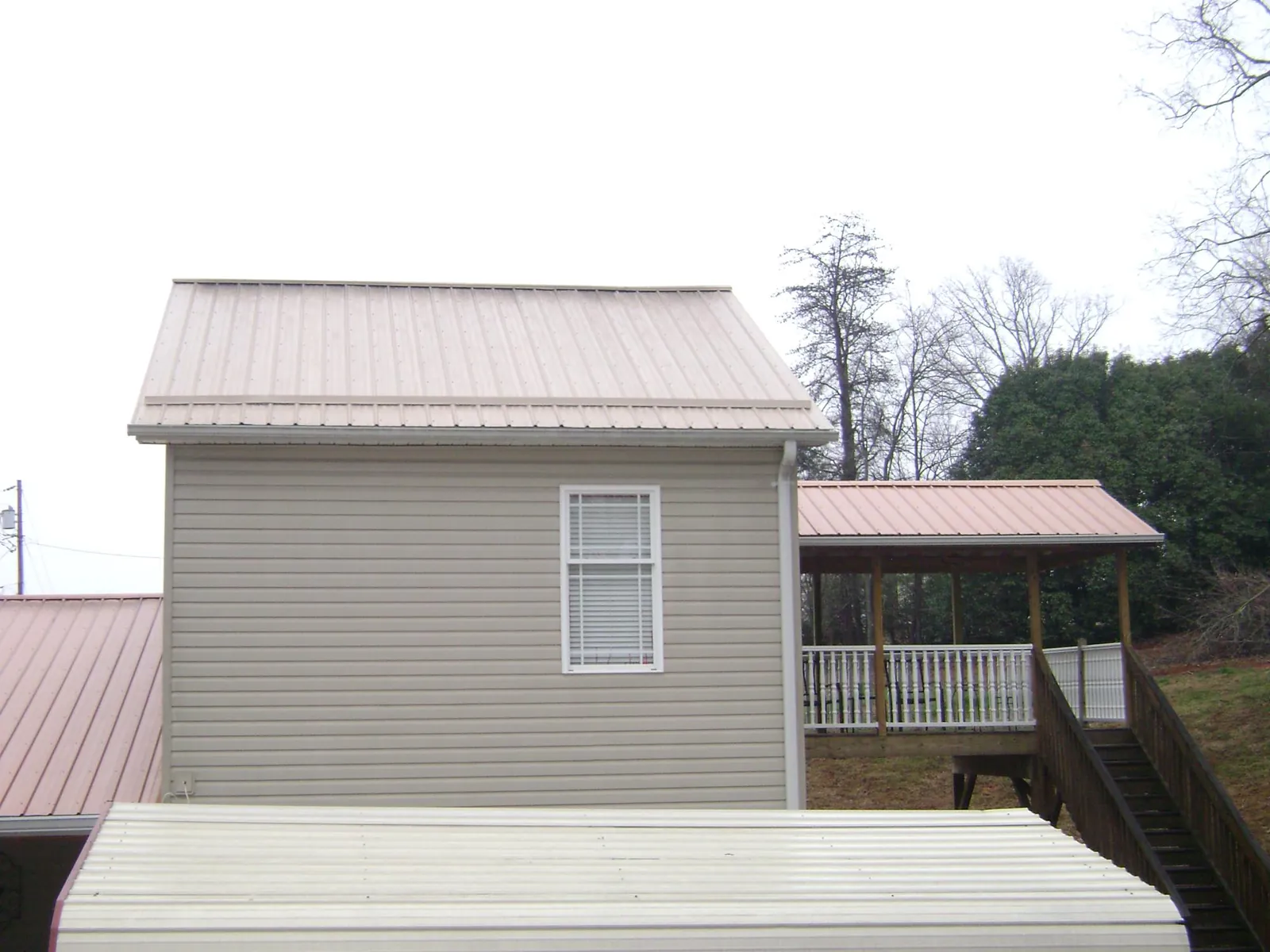 Tan metal roofs on a two story addition and attached porch, from a Roof Replacement job in Ashippun