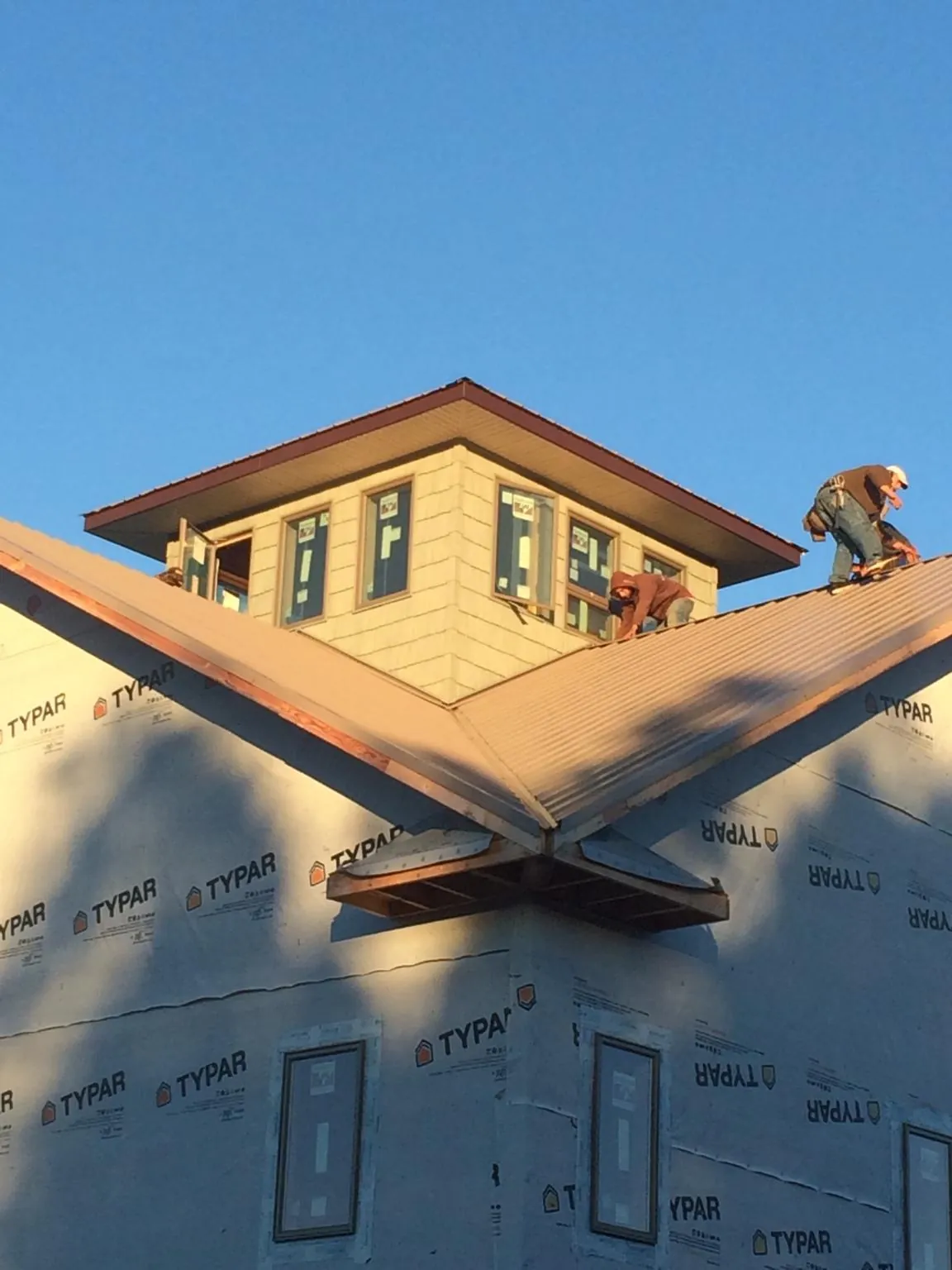 Roofers working around a rooftop cupola on a new metal roof at sunset — Roof Waterproofing in Ashippun by Roofing Brothers